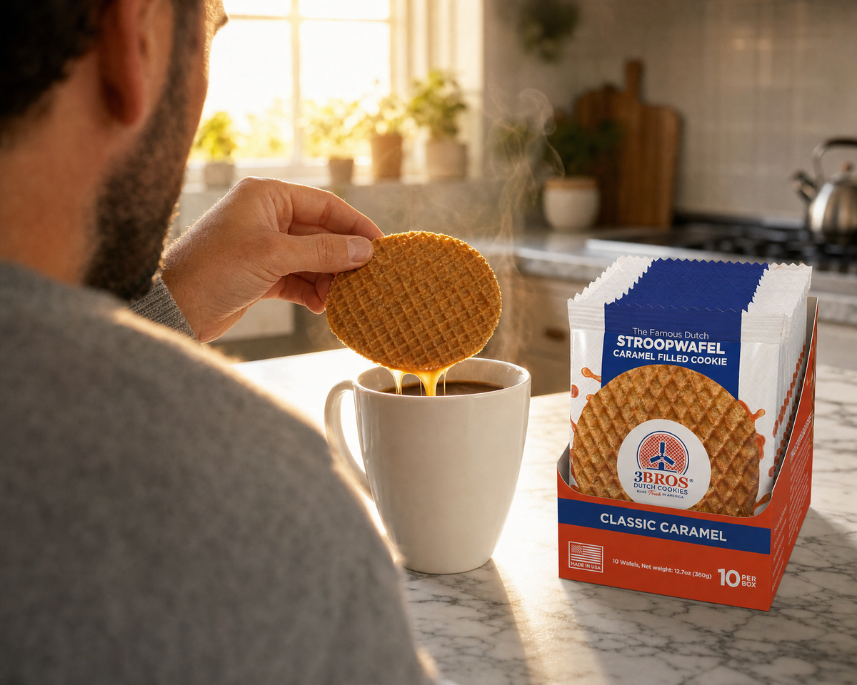 Close-up of a caramel stroopwafel warming over a coffee mug next to a 3 Bros Classic Caramel box